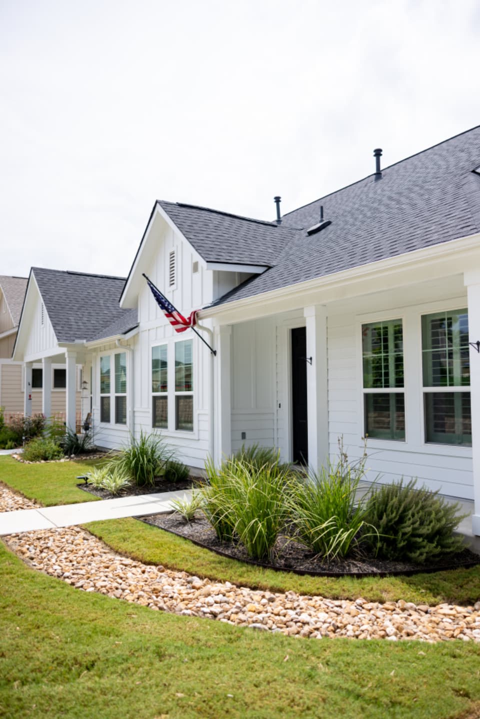 Manicured lawn with fresh mulch beds, ornamental grasses and stone border
